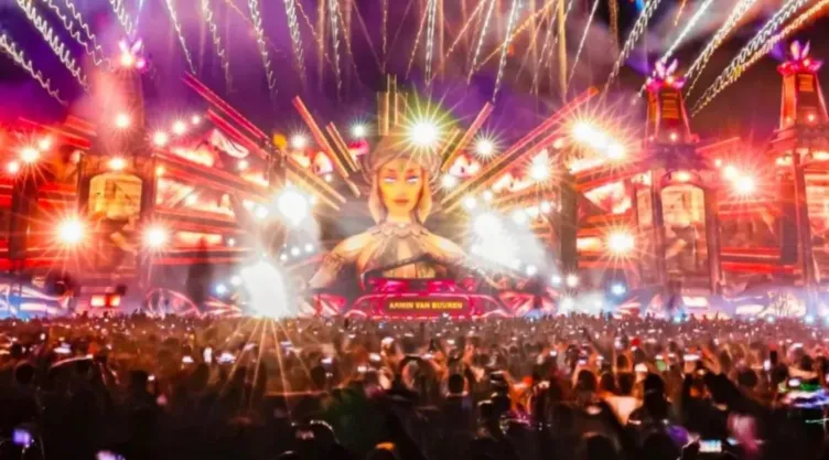 Escenario de festival musical con luces y escenografía con publico alzando las manos y disfrutando
