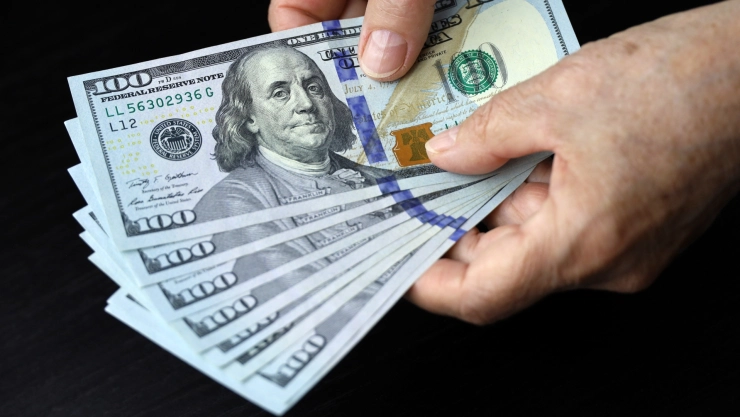 Un hombre cuenta billetes de 100 dólares.