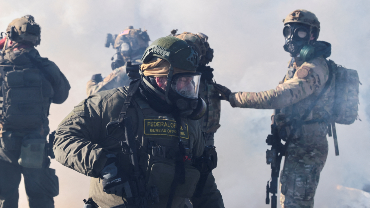 Agentes federales se mantienen en medio de gases lacrimógenos para dispersar a las personas reunidas cerca de la escena donde agentes federales dispararon fatalmente a un hombre mientras intentaban detenerlo, en Minneapolis, Minnesota , EE. UU., el 24 de enero de 2026.
