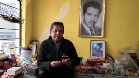 Fernando González mostrando un luchador de plástico frente a foto de su padre