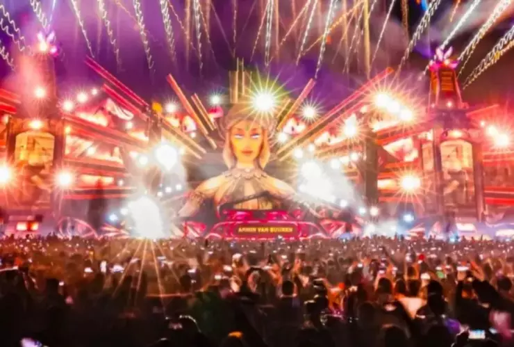 Escenario de festival musical con luces y escenografía con publico alzando las manos y disfrutando