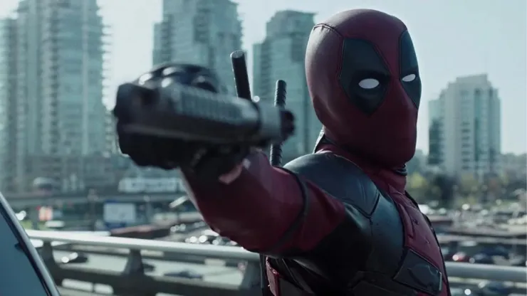 En la imagen, una captura de una escena de la primera película de ‘Deadpool’ peleando con su arma