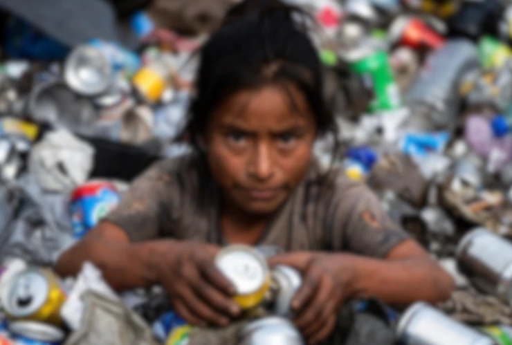 Niña juntando latas en la basura