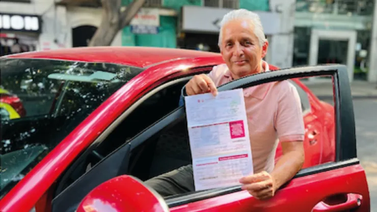 Un hombre muestra su boleta de la tenencia vehicular como muestra de su pago en Edomex 2025.