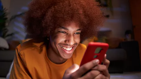 Young man at home using cellphone watching social media apps.