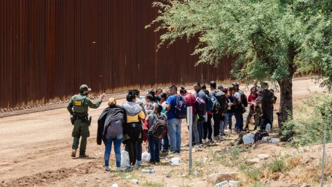 Un grupo de migrantes frente a un policía en la frontera entre México y el estado de Arizona.