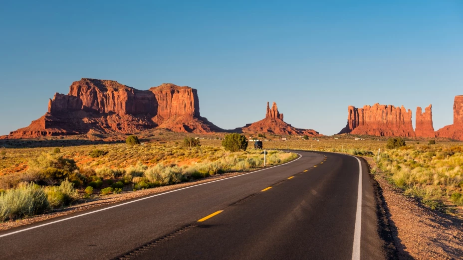 Una carretera desierta en Arizona con el fondo de montañas rocosas de color rojizo