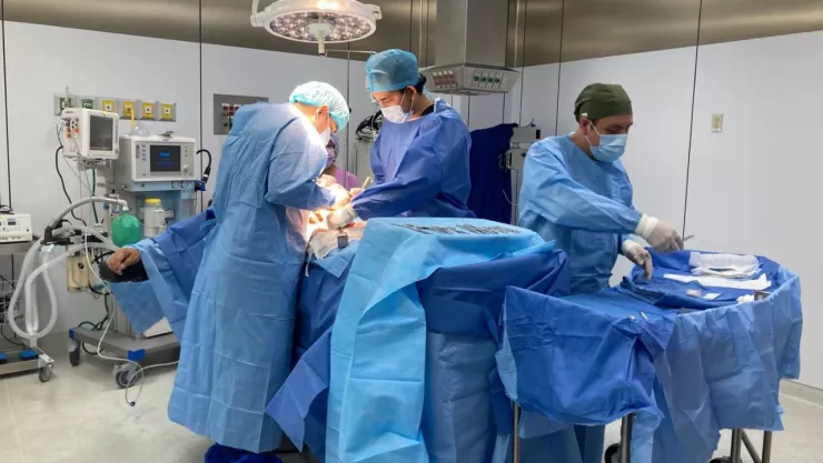 Médicos en quirófano con uniforme azul.