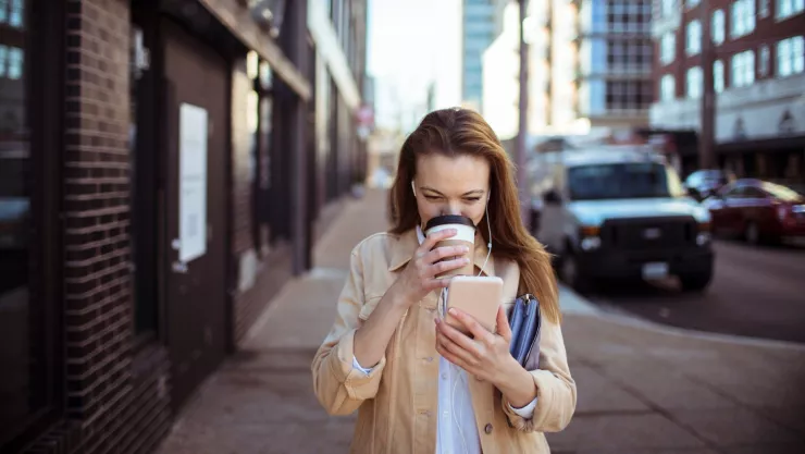 Una mujer camina mientras mira su teléfono celular.