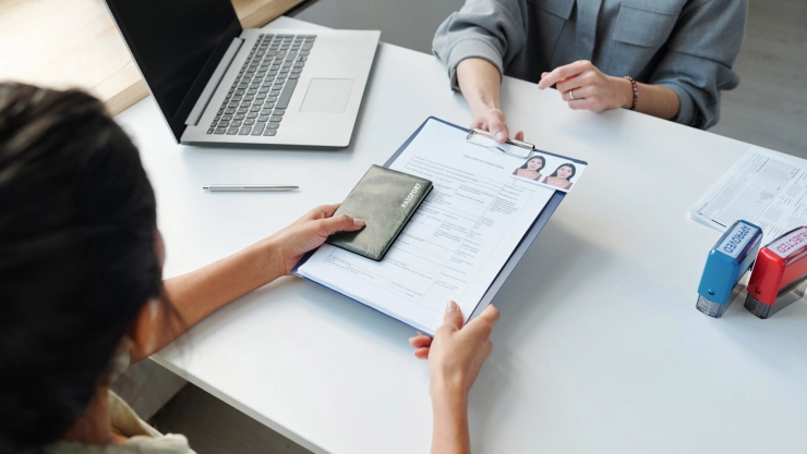 Una mujer entrega su documentación a una funcionaria del USCIS.