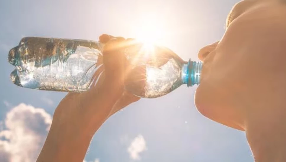 Mujer bebiendo una botella con agua por el calor.