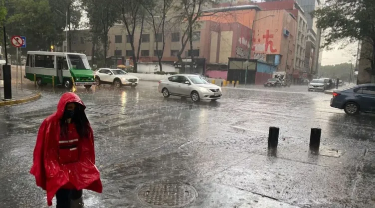 Mujer con impermeable rojo camina en plena tormenta en la CDMX.