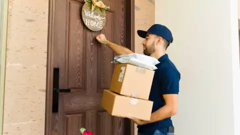 un repartidor entrega un paquete a un hogar familiar