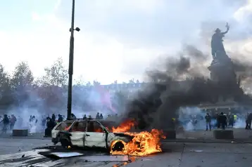 Un auto arde en París durante una protesta contra el alto costo de vida.