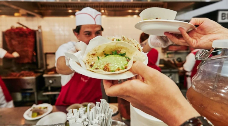 Taquero sostiene dos platos con tacos.