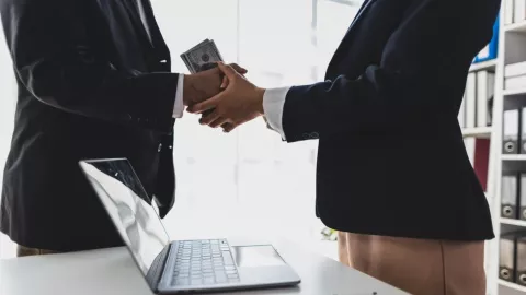 Una persona entrega un salario a otra.