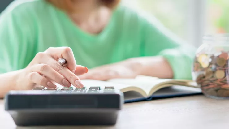 mujer preparando su declaración de impuestos con una calculadora y monedas