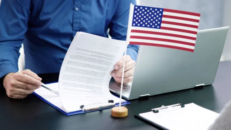 Una persona revisa una solicitud junto a una bandera de Estados Unidos.