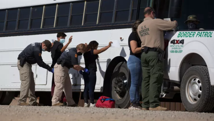 Migrantes que cruzaron la frontera son revisados por agentes de la Patrulla Fronteriza.