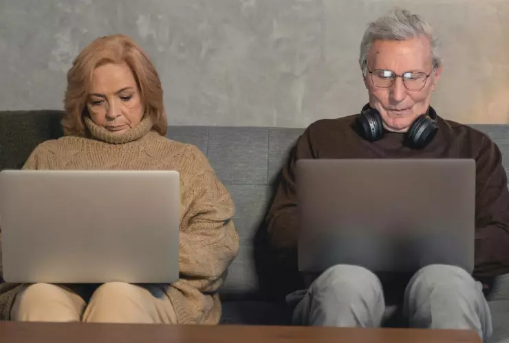 Dos adultos mayores trabajando en una computadora desde su casa