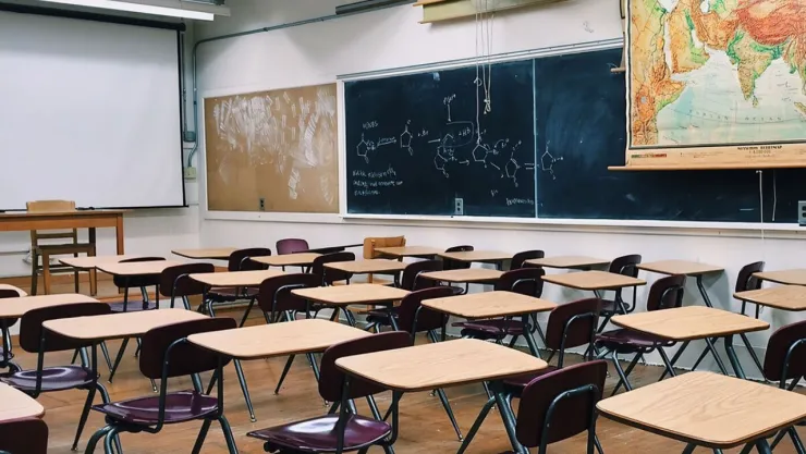 Pupitres vacíos en un salón de clases en reflejo del megapuente de la SEP.