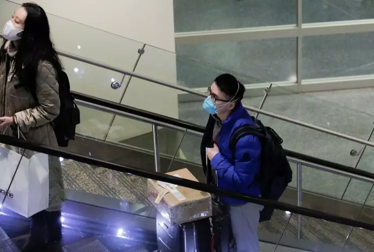 Travellers wearing masks arrive on a direct flight from China at Seattle-Tacoma International Airport