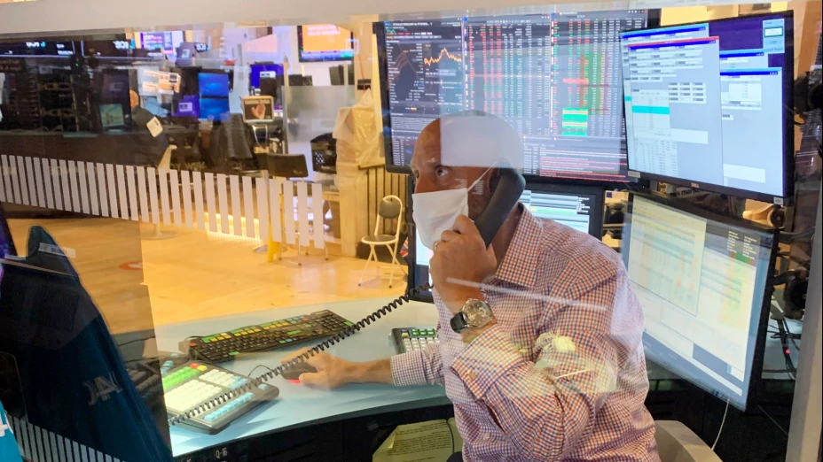 Wall Street, trabajador detrás de barrera de plástico por coronavirus.jpg
