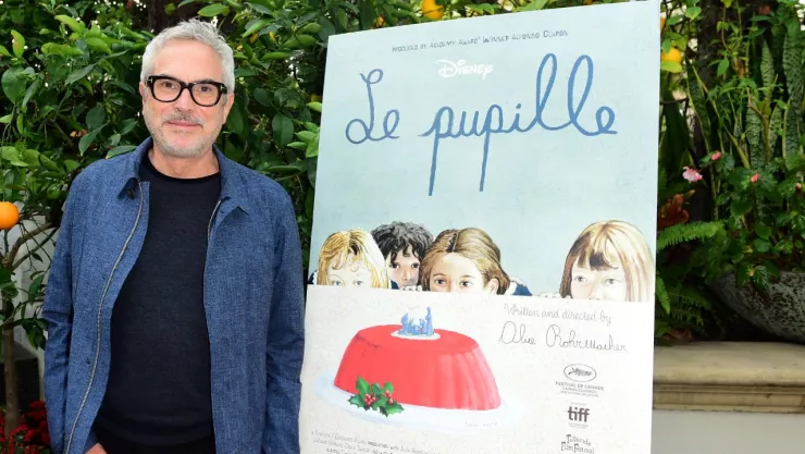 Alfonso Cuarón junto a un cartel de la producción de Le Pupille