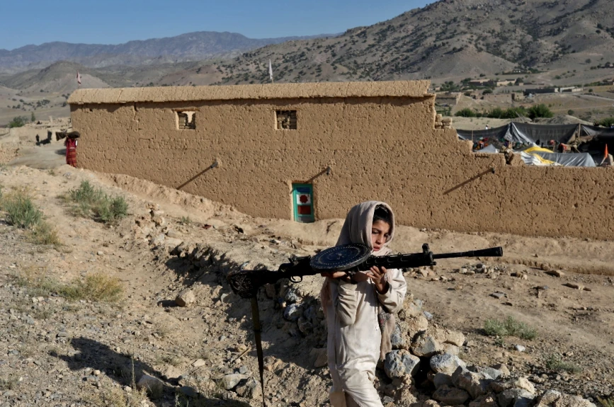 Un niño afgano lleva un arma en la zona afectada por el terremoto de la aldea de Wor Kali, en la provincia de Paktika, Afganistán.