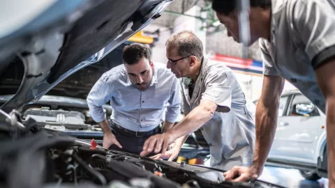 personas observando el motor de una vehículo