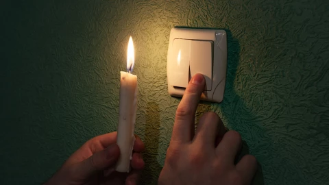 Una persona con una vela ante un corte de red eléctrica.