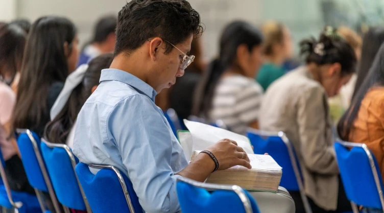 Joven de camisa azul leyendo en público.