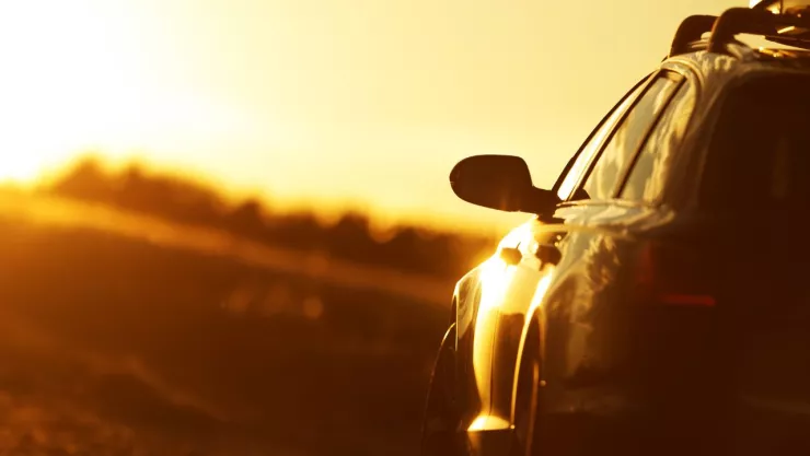 en el horizonte se observa un fuerte rayo de sol y en la parte inferior derecha un carro