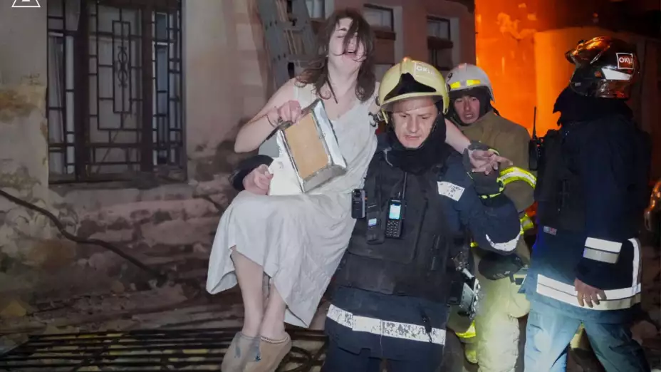Bombero evacúa a una mujer tras un ataque aéreo ruso, en Odesa, Ucrania.
