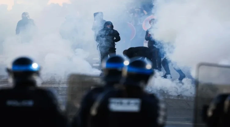 Agentes de policía se encuentran frente a los manifestantes en medio de gases lacrimógenos mientras los manifestantes llevan a cabo un bloqueo cerca del instituto Kerichen en Brest, al oeste de Francia.