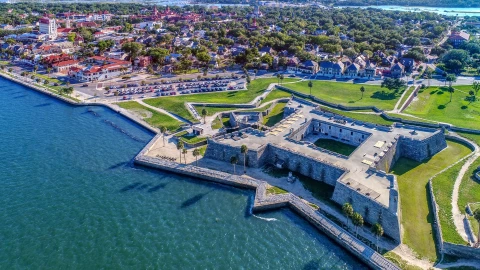 Vista aérea de una ciudad costera de Florida, con aguas claras, un castillo a la vera del mar y las pequeñas casas a lo lejos
