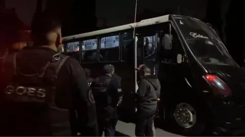 personal de seguridad resguardando un autobús en el que se transporta a migrantes