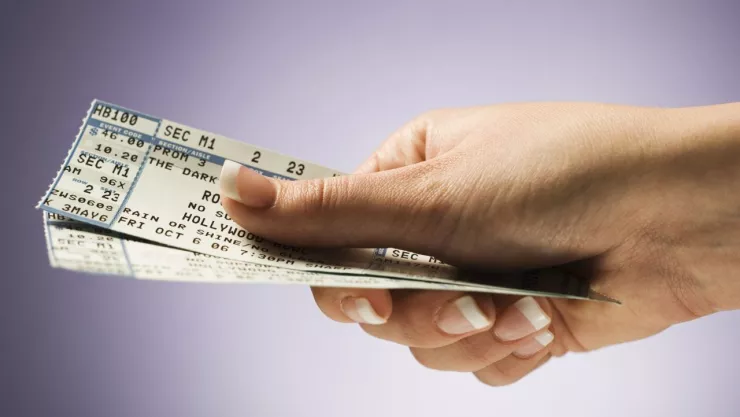 mano de una mujer sosteniendo unos boletos