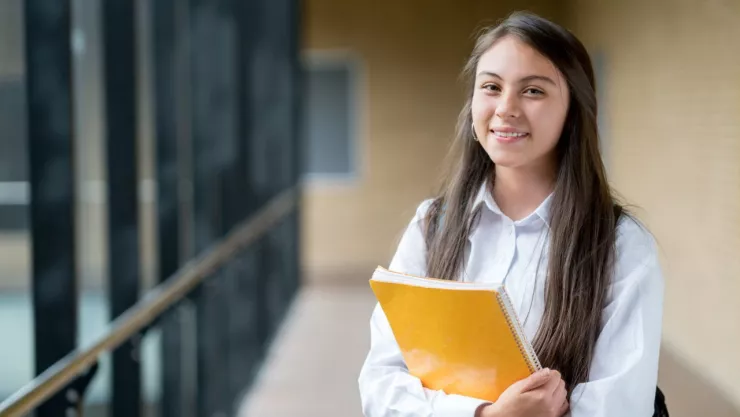 joven sosteniendo un cuaderno amarillo