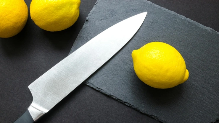 Cuchillo filoso sobre tabla de madera con limones a un lado.jpg