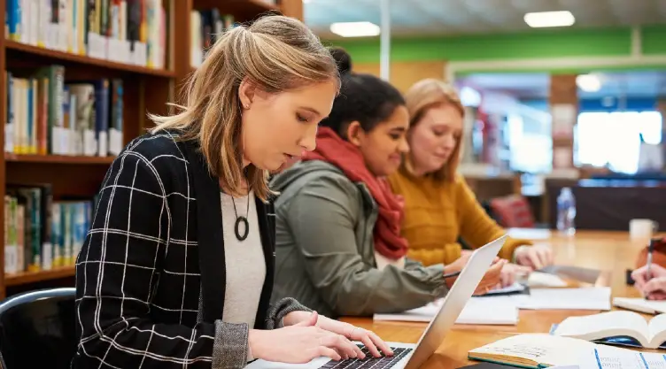 alumnos estudian en la biblioteca de su universidad privada