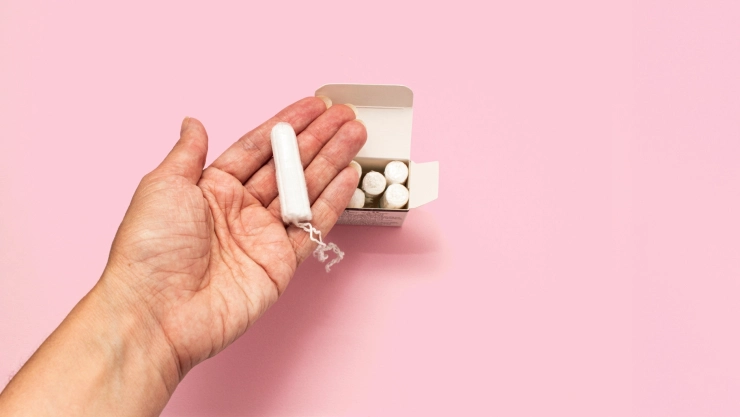 Una mujer muestra un tampax en su mano sobre una caja
