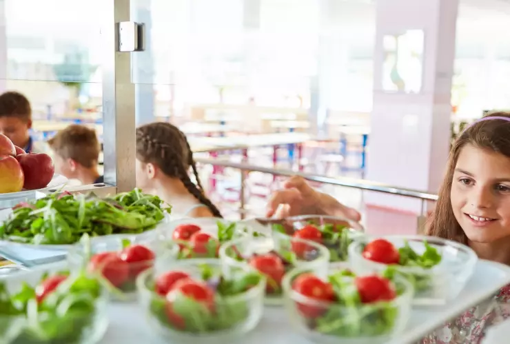 Una niña escoge un plato de comida en la escuela