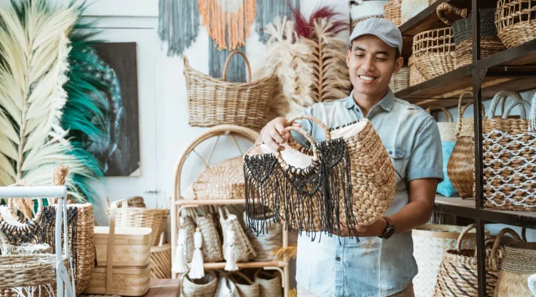 Un hombre mira uno de los bolsos artesanales que vende en su negocio, en Estados Unidos.
