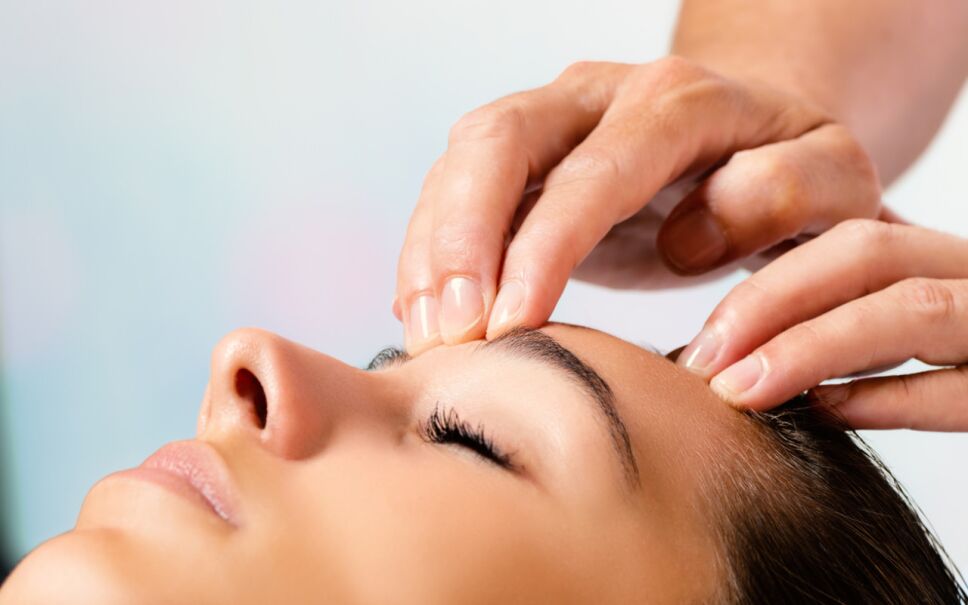 Hands doing massage on forehead.