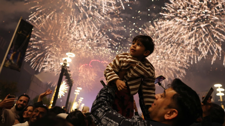 Un niño mira hacia arriba mientras explotan los fuegos artificiales durante las celebraciones de Año Nuevo en Lusail, Qatar