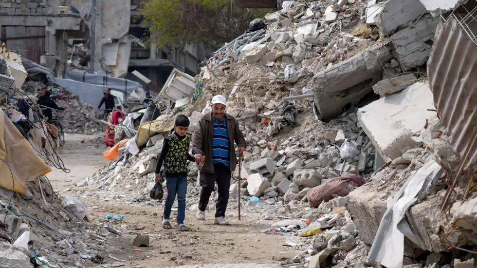 Personas caminan entre viviendas destruidas en Jabaliya.