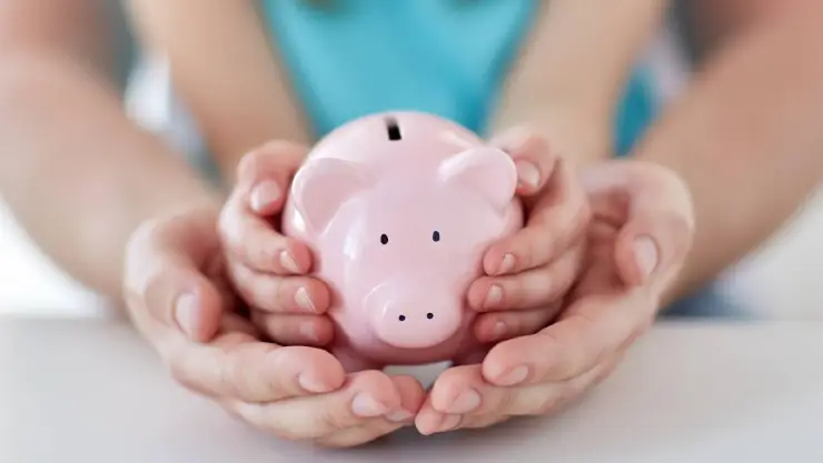 una familia sosteniendo un chanchito que almacena dinero
