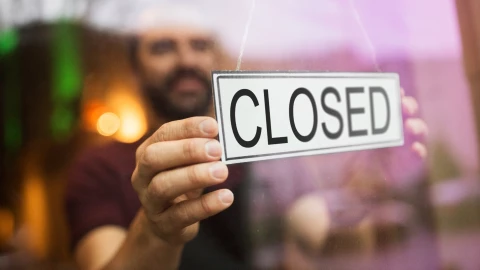 un hombre pone un cartel que dice cerrado