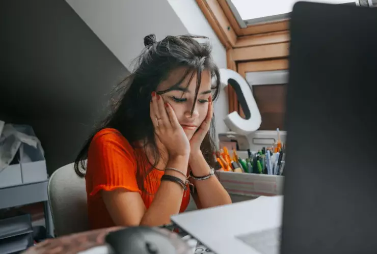 jóven con cara de aburrimiento o decepción frente a la computadora